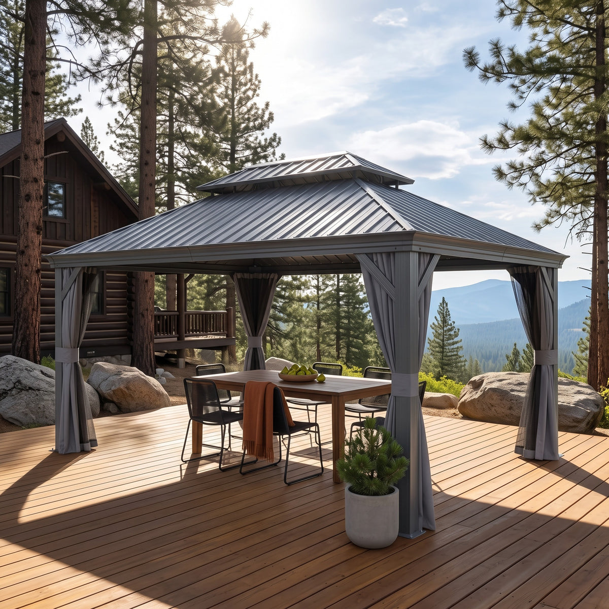Gray aluminum 12x16 double roof hardtop gazebo with tied back curtains over a dining table on a wood deck by pines