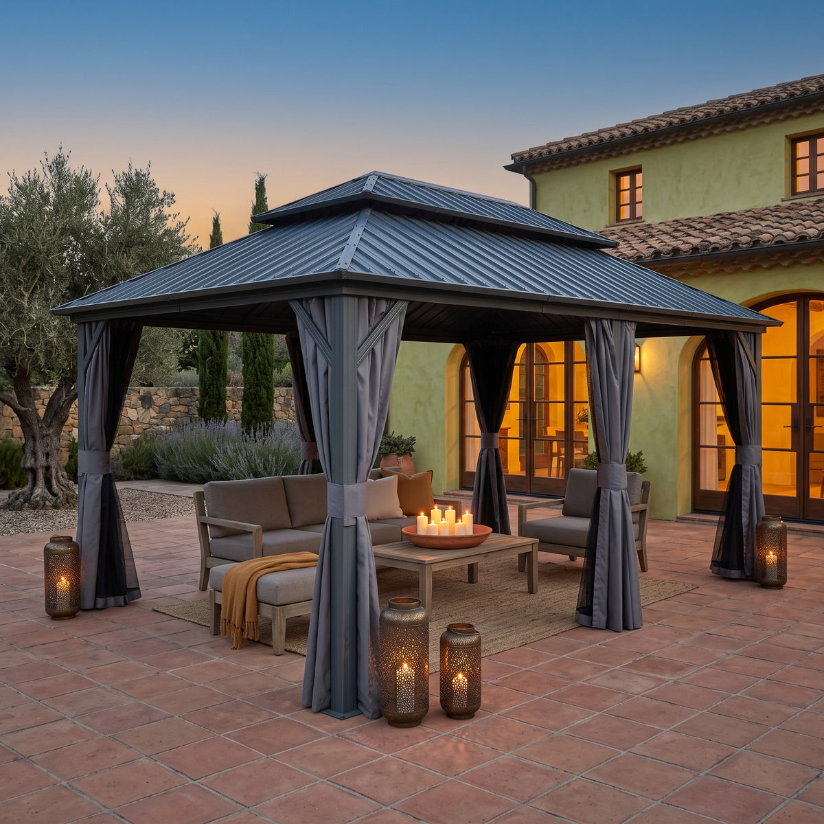 Gray aluminum 12x18 double roof hardtop gazebo with tied curtains over a lounge set on a terracotta patio at dusk