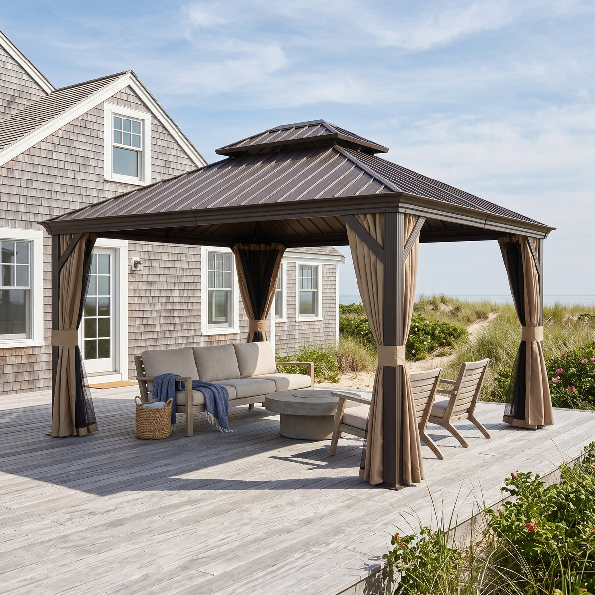 Brown steel double roof hardtop gazebo with tan curtains over a sofa and lounge chairs on a coastal deck