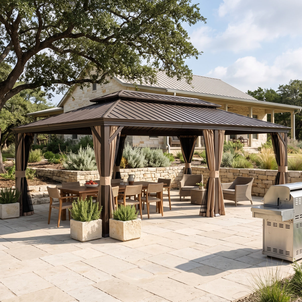 Brown metal 14x22 hardtop gazebo with tan curtains over a dining table on a stone patio by a farmhouse