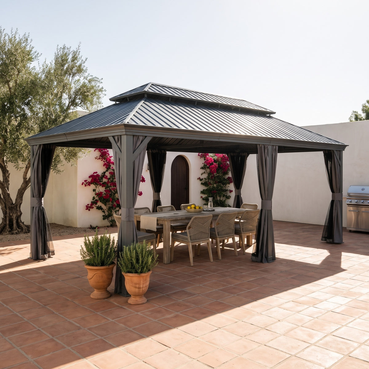 Gray aluminum 14x24 double roof hardtop gazebo with tied back curtains over a dining table on a terracotta patio