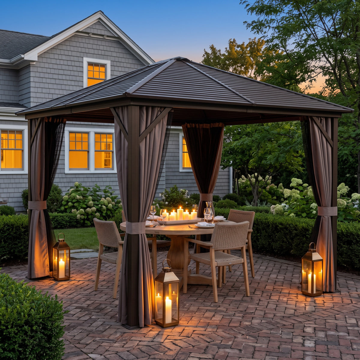 Bronze aluminum hardtop gazebo with taupe curtains over a candlelit dining table on a brick patio at dusk