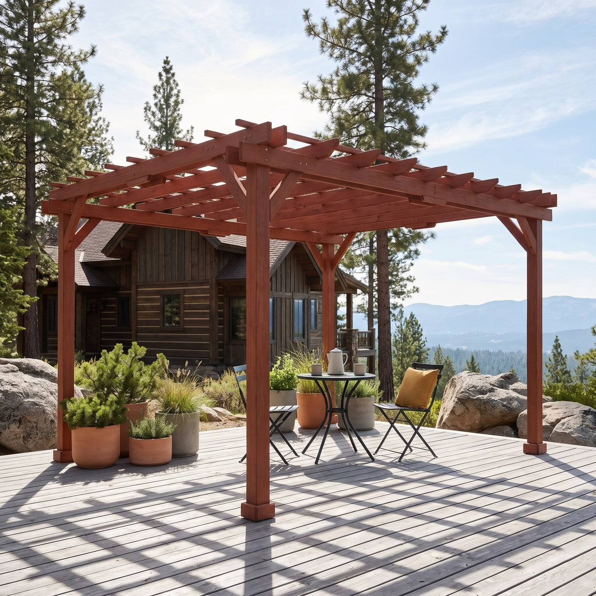 Brown wood pergola over a bistro table on a gray deck beside a mountain cabin on a sunny day