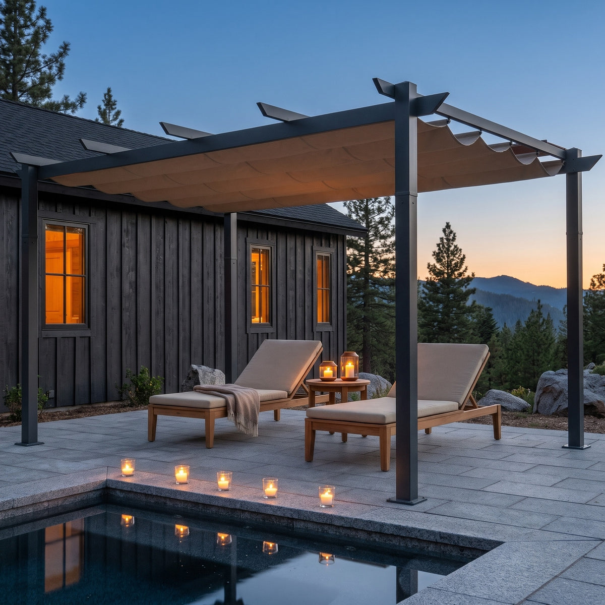 Dark gray aluminum pergola with tan retractable canopy over two lounge chairs beside a pool at dusk