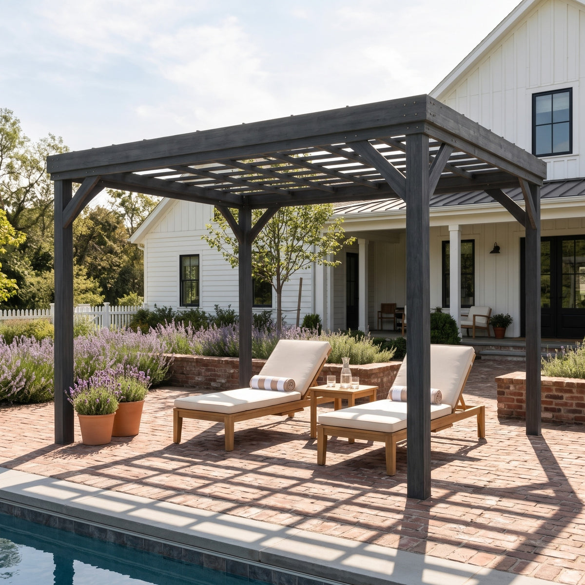 Gray wood pergola with open grid roof shading two cushioned loungers on a brick patio beside a pool