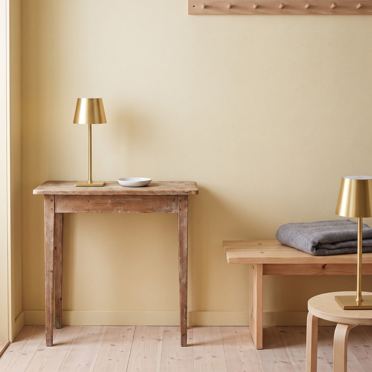 Two gold cordless table lamps on a rustic wood console and a birch stool beside a pine bench