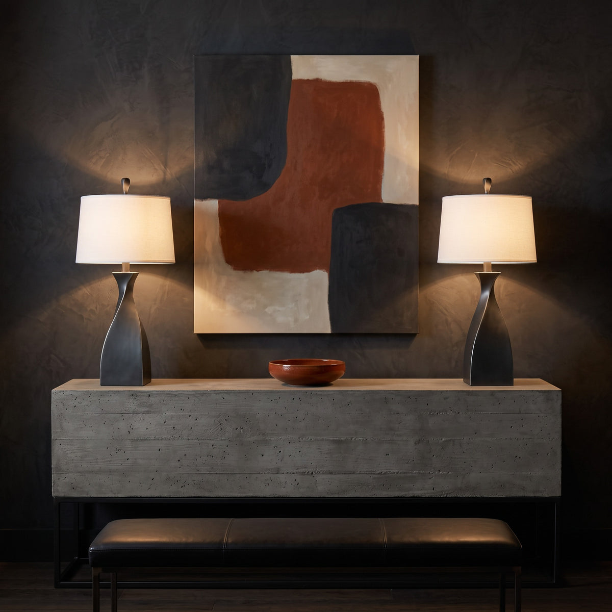 Pair of grey twisted base table lamps with white linen drum shades, lit, on a concrete console