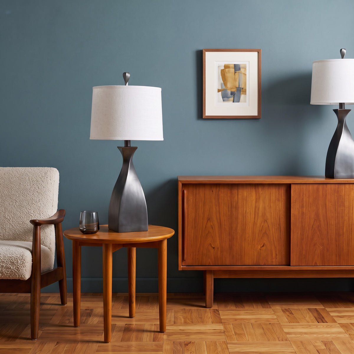 Pair of grey twist base table lamps with white linen drum shades on a wood side table and sideboard