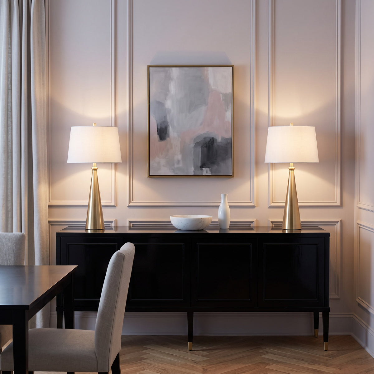 Two gold cone table lamps with white linen shades, lit, on a black sideboard in a paneled dining room