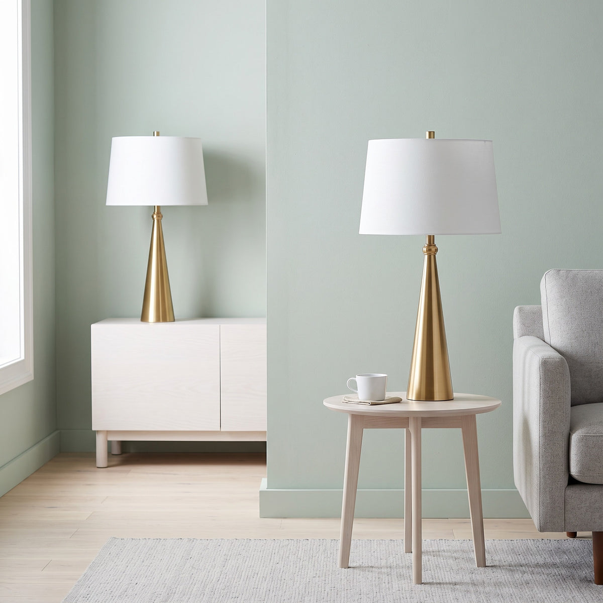 Pair of gold cone table lamps with white linen shades on a white cabinet and a round side table in a sage green room