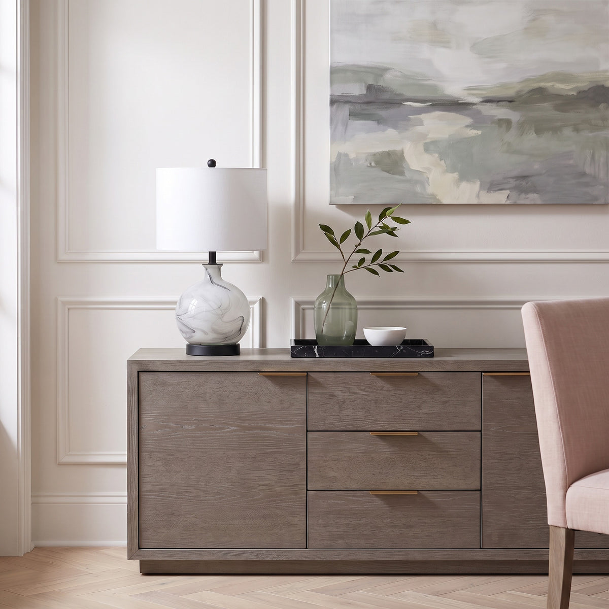 White and gray swirled glass table lamp with white linen drum shade on a gray oak sideboard