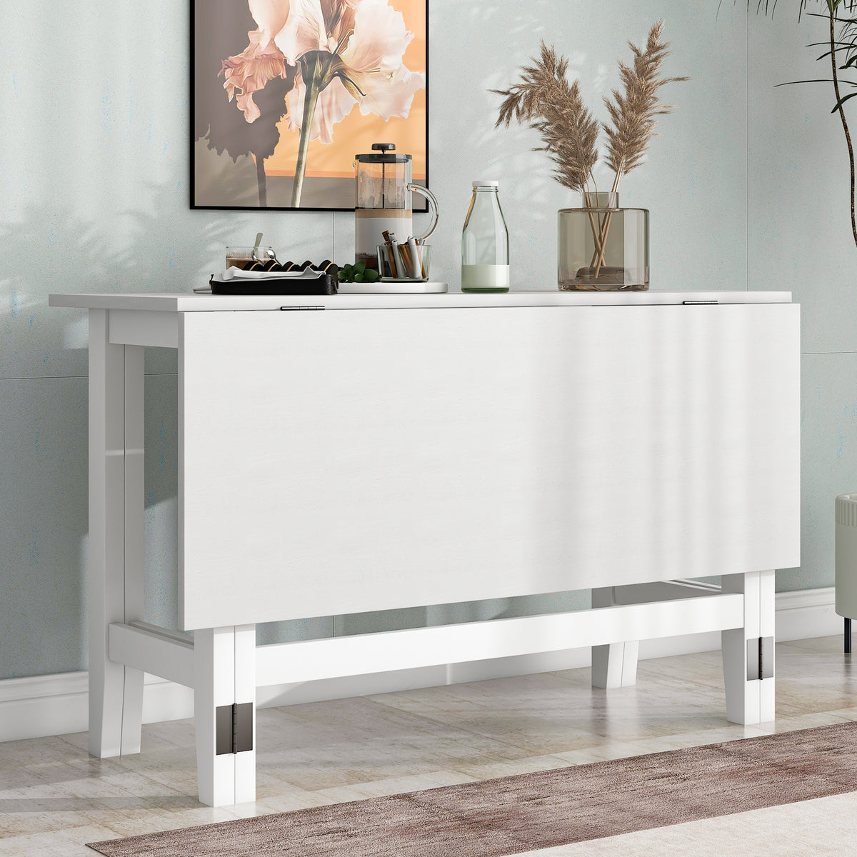 White farmhouse drop-leaf dining table folded as a narrow console against a wall with coffee accessories