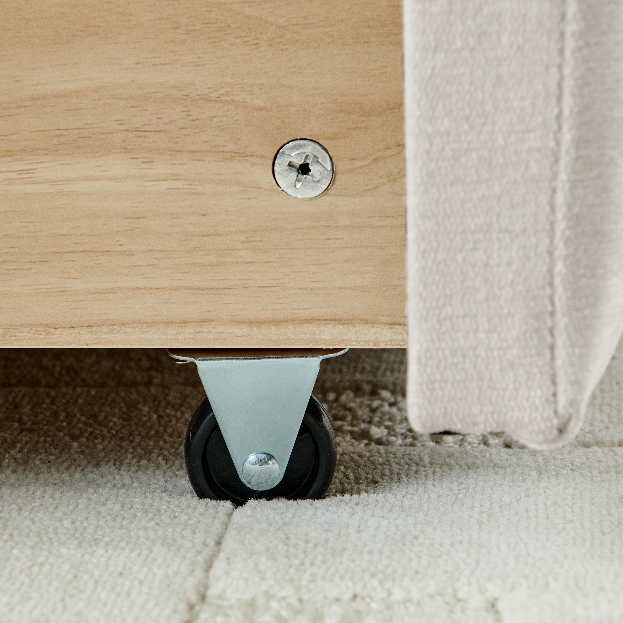 Close-up of tufted beige chenille footboard corner and leg