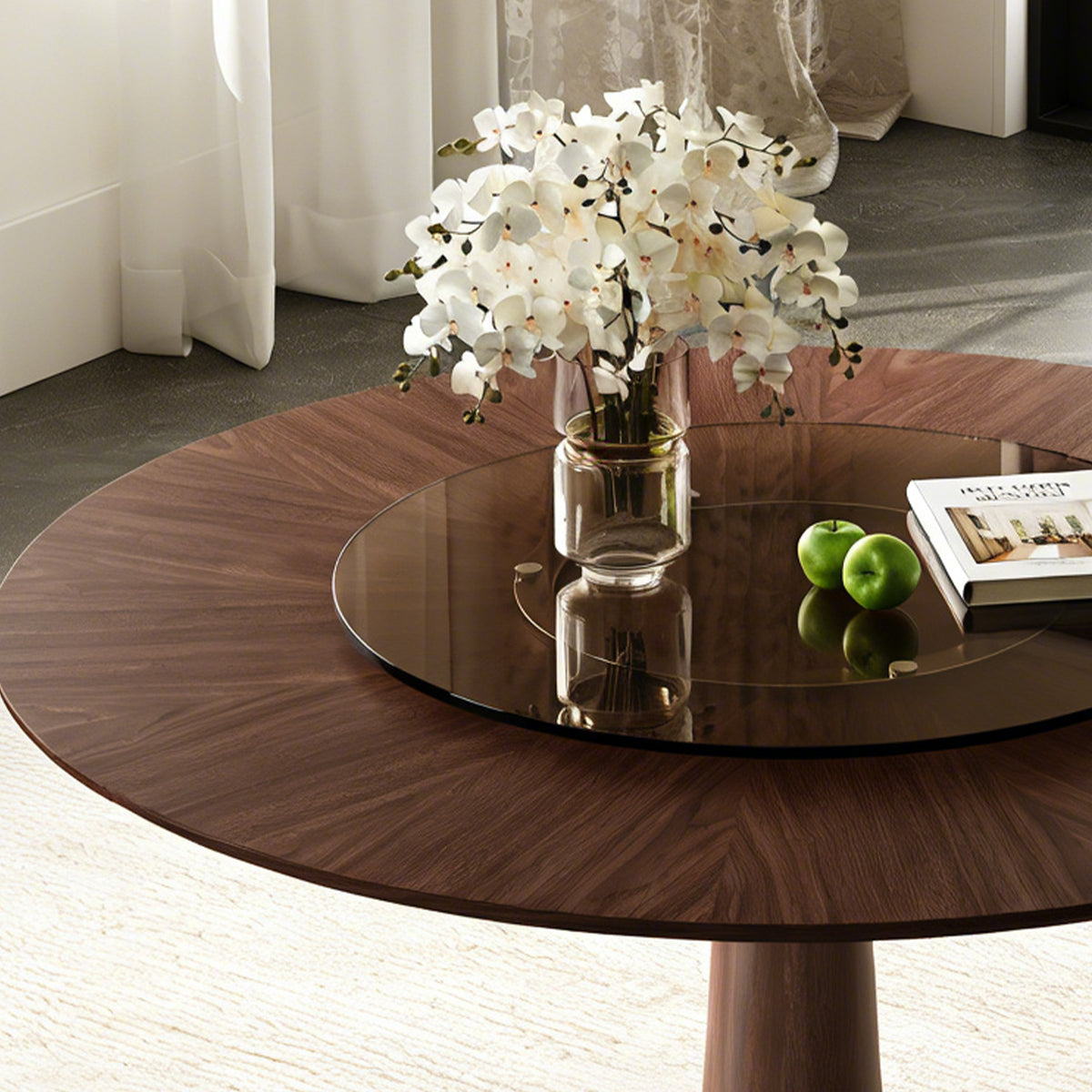 Close-up of the walnut tabletop and brown glass turntable holding orchids, apples and a book
