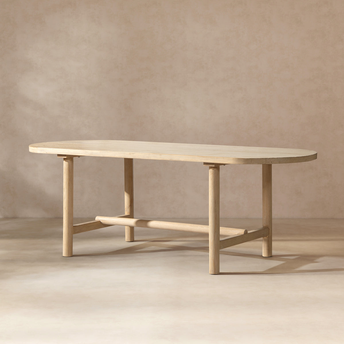 Natural cerused pine oval dining table, three-quarter view on beige studio background