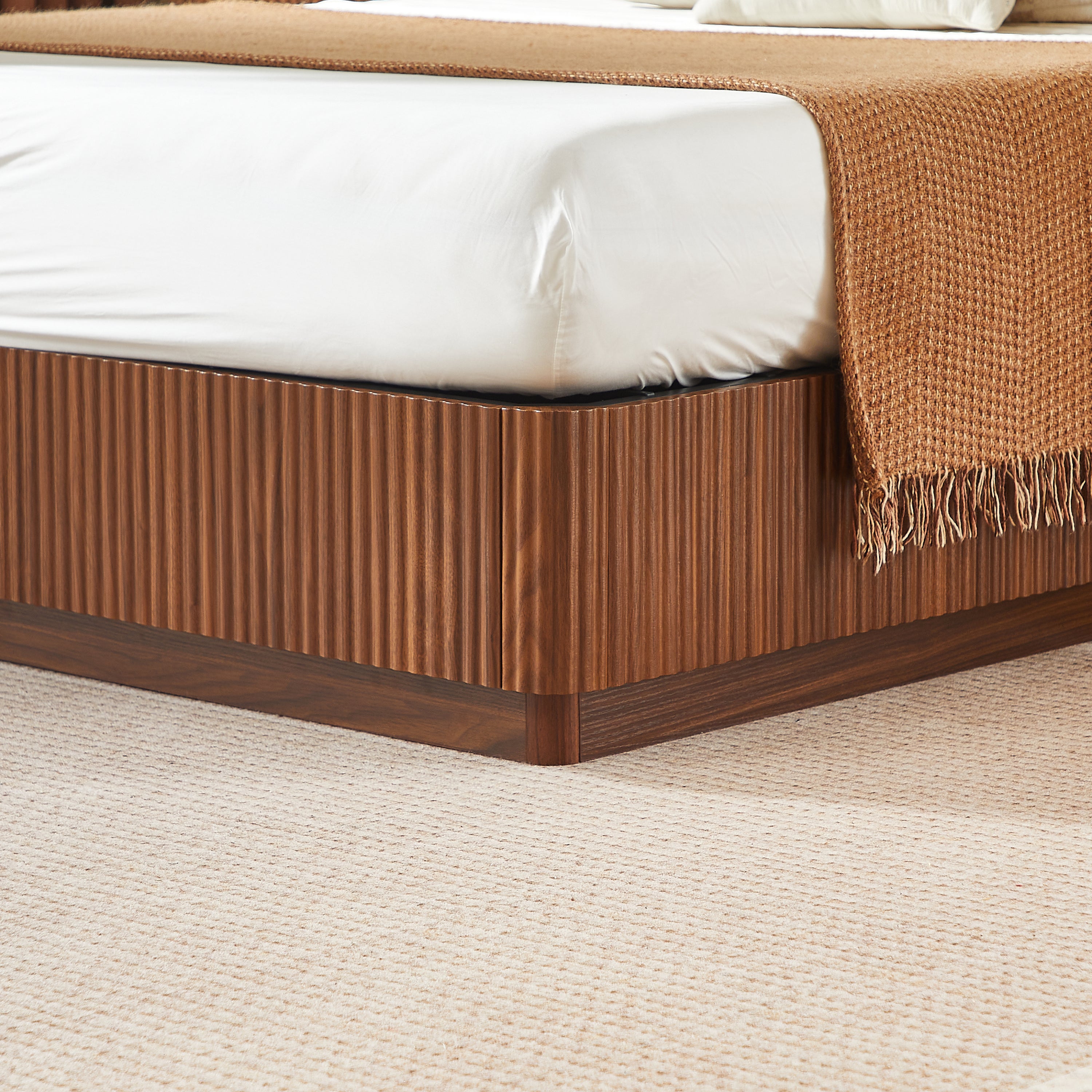 Foot-corner close-up of the walnut corrugated plinth base low to the carpet #Color_Walnut