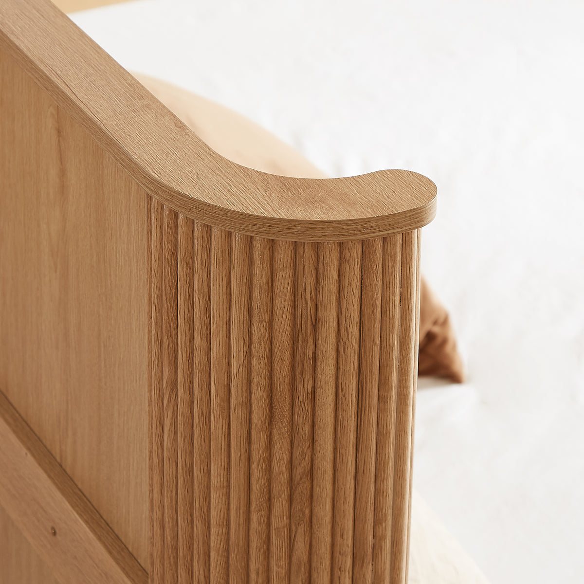 Detail of the rounded eave top corner and vertical fluting on the natural oak headboard