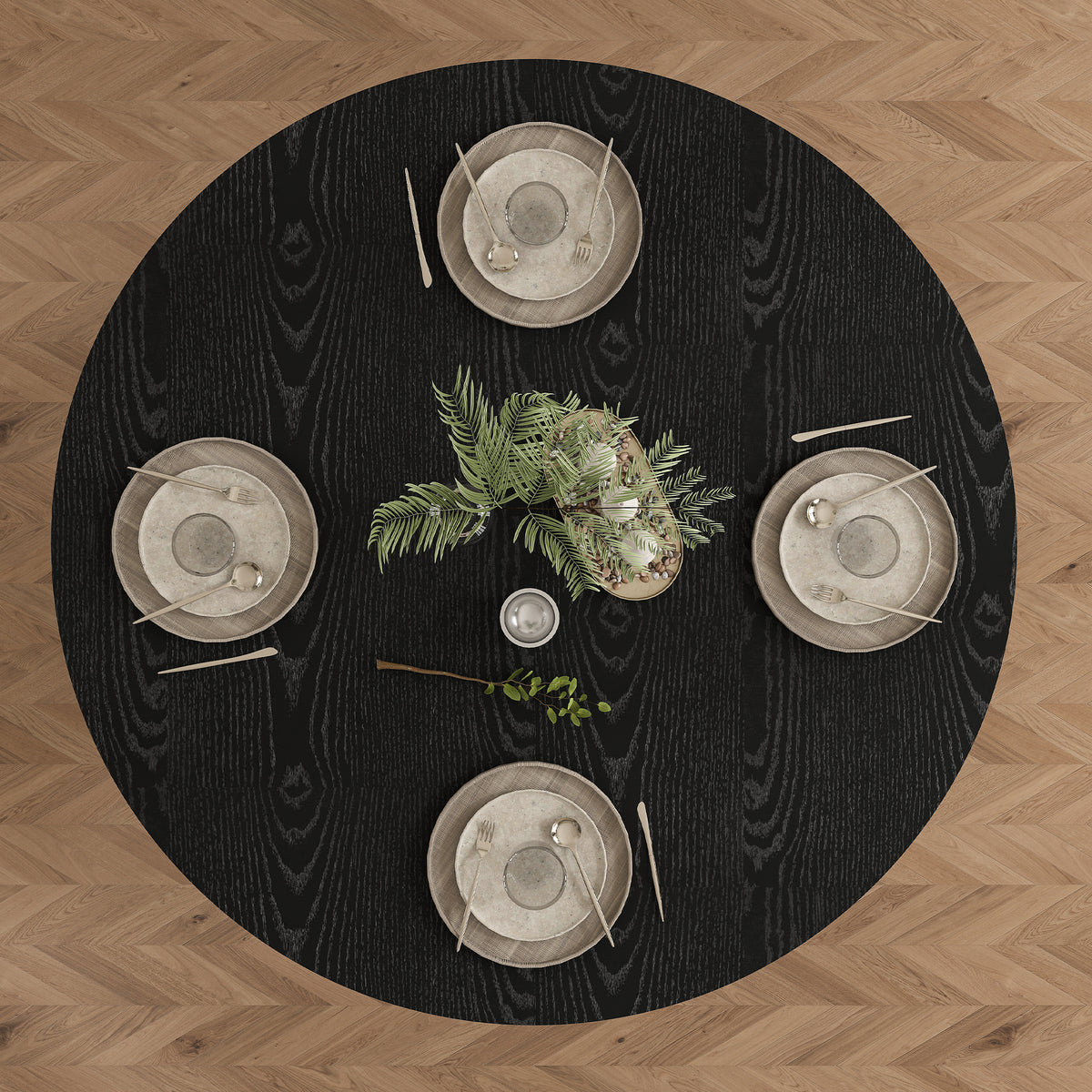 Overhead view of black round dining table set for four on a herringbone wood floor