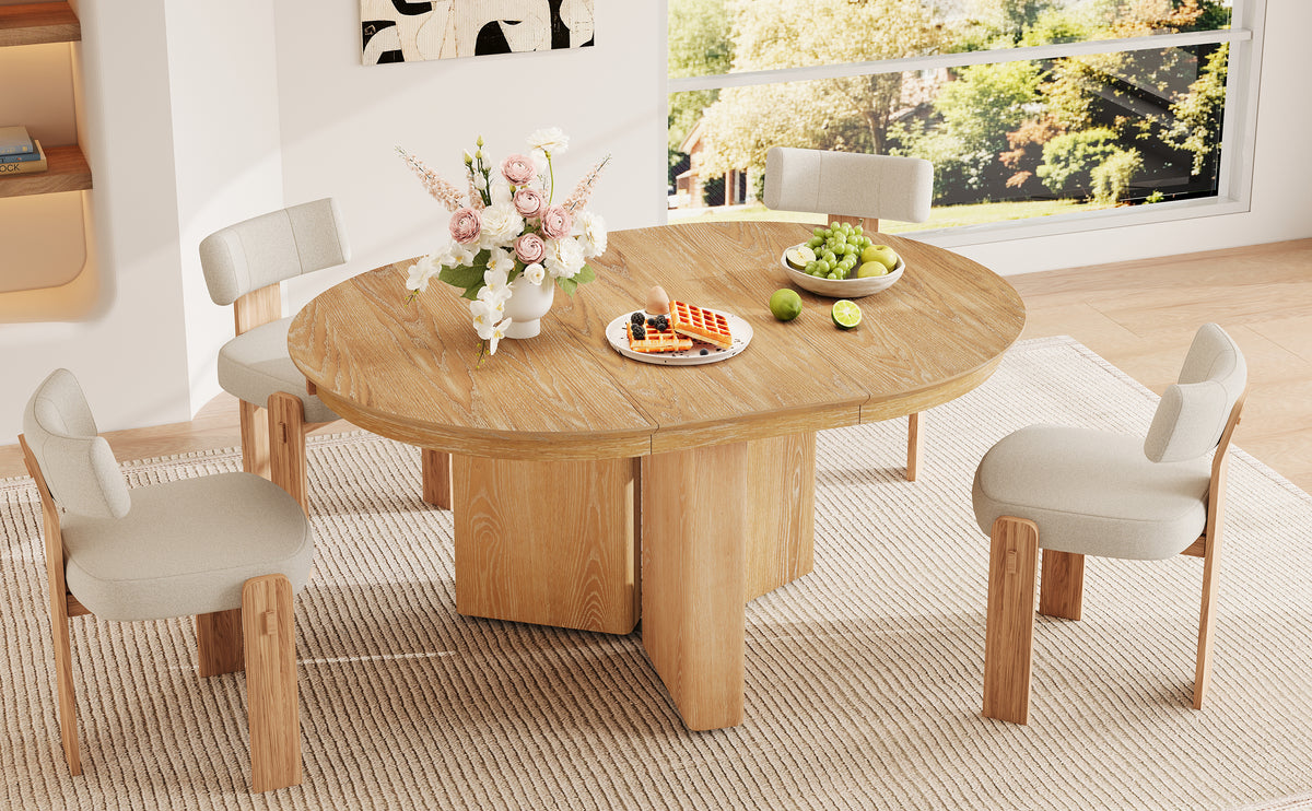 Round natural oak table with four cream chairs near lit shelving and a window